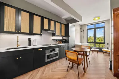 a kitchen with black cabinets and a table with chairs at Freeman 503 by Rove Travel - 1BR Condo with Shared Amenities in New York
