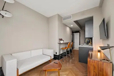 a living room with a white couch and a kitchen at Freeman 903 by Rove Travel - 1BR Condo with Shared Amenities in New York