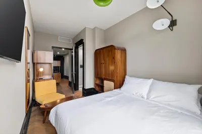 a bedroom with a white bed and a chair at Freeman 903 by Rove Travel - 1BR Condo with Shared Amenities in New York