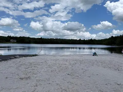 a person sitting on a beach near a lake at Poconos Retreat Hot Tub, Pool, Theater EV chrg & more in Blakeslee