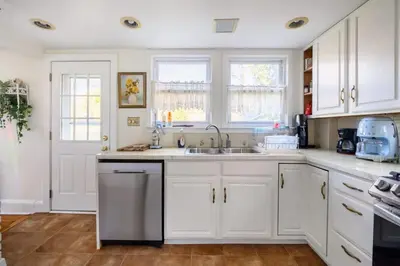a kitchen with white cabinets and a sink at Charming & Whimsical Historic River Home in Titusville