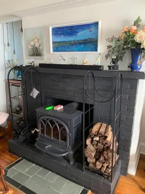 a black brick fireplace with a pile of wood at Charming & Whimsical Historic River Home in Titusville