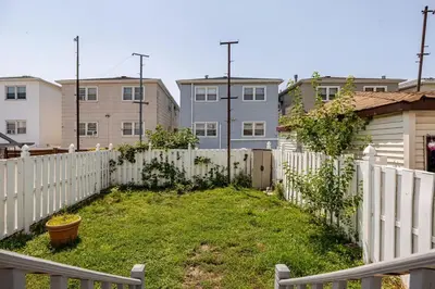 a backyard with a white fence and some buildings at Free Parking -5 Guests- 30 min to NYC in Bayonne