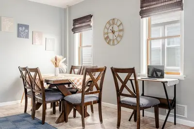 a dining room with a table and chairs and a clock at Free Parking -5 Guests- 30 min to NYC in Bayonne