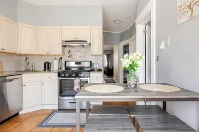 a kitchen with white cabinets and a table with flowers at Free Parking -5 Guests- 30 min to NYC in Bayonne