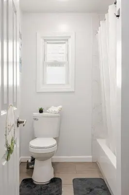 a white bathroom with a toilet and a window at Free Parking -5 Guests- 30 min to NYC in Bayonne