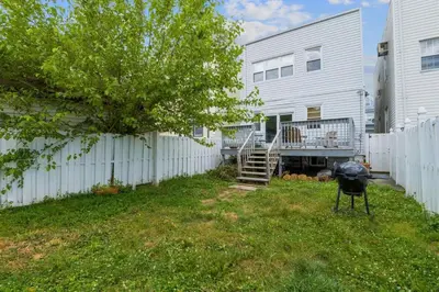 a backyard with a white fence and a grill at Free Parking -5 Guests- 30 min to NYC in Bayonne