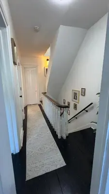 a hallway with a white staircase with a white rug at Bright & Spacious Home close to NYC and World Cup in Bayonne