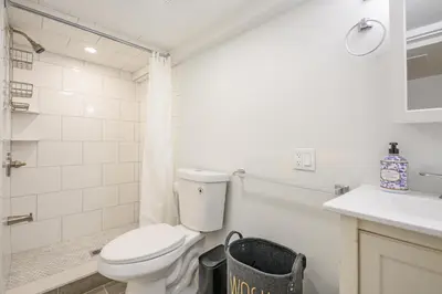 a white bathroom with a toilet and a sink at 20 Mins to Times Sq. EWR | Cozy Apartment | Sleeps 4 in Jersey City
