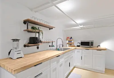 a kitchen with white cabinets and a wooden counter top at 20 Mins to Times Sq. EWR | Cozy Apartment | Sleeps 4 in Jersey City