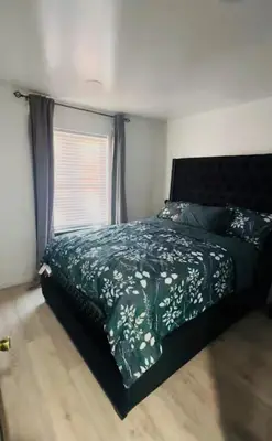 a bedroom with a bed with a green bedspread and a window at Cozy Home 3BR-2Bath near EWR NYC DreamMall MetLife in Newark