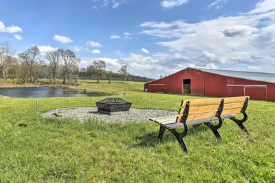 a bench sitting in the grass next to a red barn at Cottage and Suite Close to Camps and Ski Resorts in Pleasant Mount