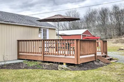 a wooden deck with an umbrella on a house at Deluxe Duplex close to Ski Runs in Pleasant Mount