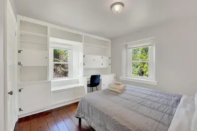 a white bedroom with a bed and two windows at Spacious 5-Bed Retreat in Charming Kennett Square in Kennett Square