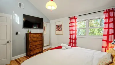 a bedroom with a large white bed with red curtains at Sleeps 13 Private Sauna Hot Tub Game Room in Thornhurst