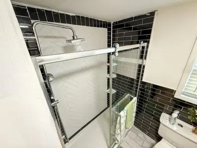 a shower with a glass door in a bathroom at New 3 BR Apt in Elizabeth Railroad Style Path Train Bus Hospital EWR Airport NJ Manhattan NYC in Elizabeth