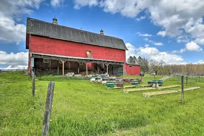 a red barn in a field with a fence at Countryside Retreat Close to Ski Slopes in Pleasant Mount