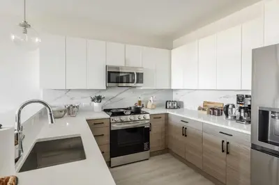 a kitchen with white cabinets and a stove top oven at Luxe Loft 15 Min from NYC with City View & Gym in Jersey City