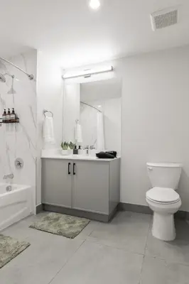 a bathroom with a toilet and a sink and a mirror at Luxe Loft 15 Min from NYC with City View & Gym in Jersey City