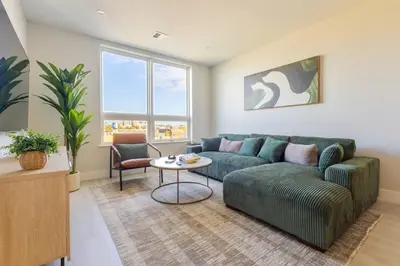 a living room with a green couch and a table at Luxe Loft 15 Min from NYC with City View & Gym in Jersey City