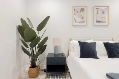 a bedroom with a white bed and a potted plant at Sleek Loft 15 Min from NYC with Manhattan View in Jersey City