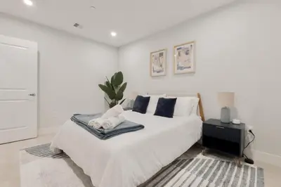 a white bedroom with a large white bed with pillows at Sleek Loft 15 Min from NYC with Manhattan View in Jersey City