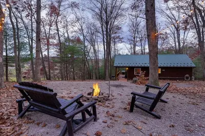 two chairs and a fire pit in front of a cabin at Mountain Bliss Cottage