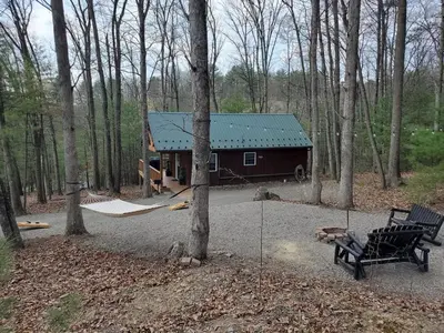 a cabin in the woods with a bench and a tree at Mountain Bliss Cottage