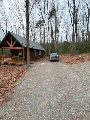 a car parked in front of a log cabin at Mountain Bliss Cottage