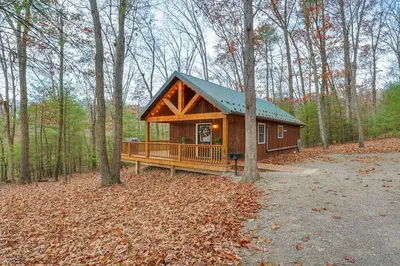 a large wooden cabin in the woods with trees at Mountain Bliss Cottage