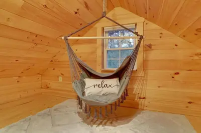 a hammock in a log cabin with a window at Mountain Bliss Cottage