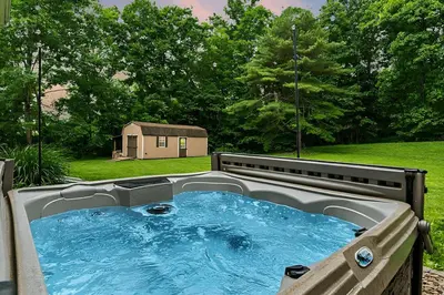 a hot tub in a yard with a house in the background at Peaceful Valley Retreat in Elliottsburg