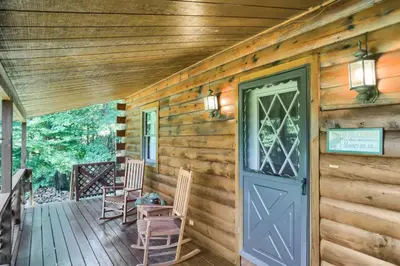 a cabin with a blue door and two chairs on a porch at Pine View Cottage in Elliottsburg