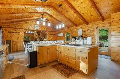 a large kitchen with wooden walls and wooden floors at Ridgetop Cabin in Elliottsburg