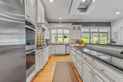 a large white kitchen with white cabinets and windows at Willow Brook Mansion in Millerstown