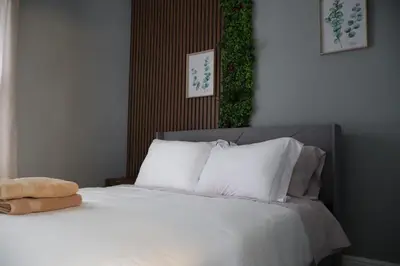 a bedroom with a bed with white sheets and pillows at Cozy Home, 19m to NYC, 10m to American Dream in Wallington