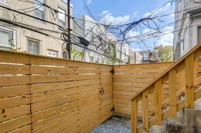 a wooden fence in front of a building at 3-Story Rowhouse with Patio! 5 Mi to Center City in Philadelphia