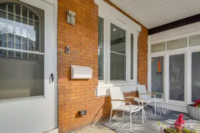 a porch with two white chairs and a window at 3-Story Rowhouse with Patio! 5 Mi to Center City in Philadelphia