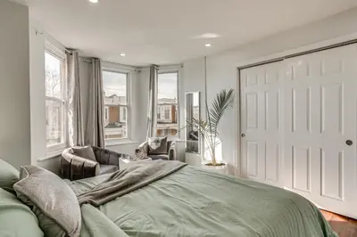 a bedroom with a bed and a door and windows at 3-Story Rowhouse with Patio! 5 Mi to Center City in Philadelphia