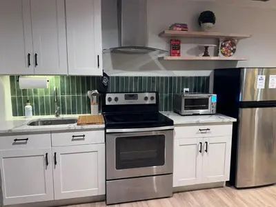 a kitchen with white cabinets and a stove top oven at New York City views! in Kearny