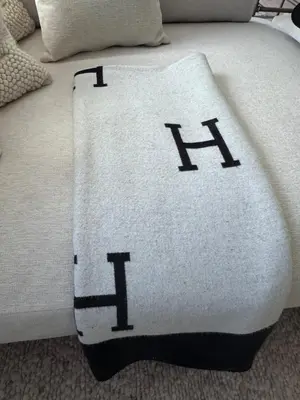 a bed with a white blanket with the letter h on it at New York City views! in Kearny