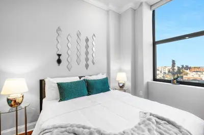 a white bedroom with a large bed and a window at Luxury Studio Loft - Rooftop View & Pool in Philadelphia