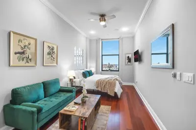 a living room with a green couch and a bed at Luxury Studio Loft - Rooftop View & Pool in Philadelphia