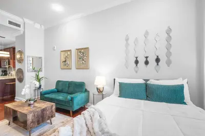 a bedroom with a large bed and a blue chair at Luxury Studio Loft - Rooftop View & Pool in Philadelphia