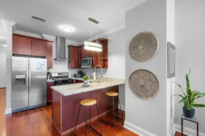 a kitchen with wooden cabinets and stainless steel appliances at Luxury Studio Loft - Rooftop View & Pool in Philadelphia