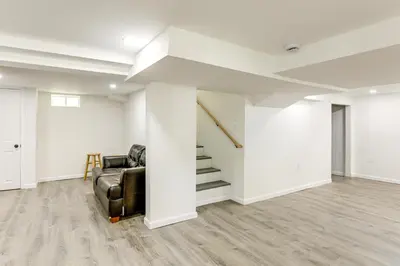 a living room with a black leather chair and stairs at Walk to River, Parks and Dining Family Home with Yard