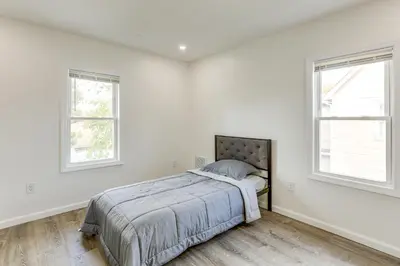 a white bedroom with a bed and two windows at Walk to River, Parks and Dining Family Home with Yard