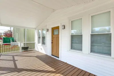 a front porch of a white house with a wooden door at Walk to River, Parks and Dining Family Home with Yard