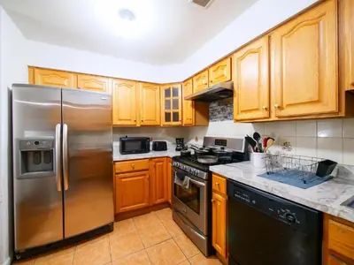 a kitchen with wooden cabinets and a stainless steel refrigerator at Bright Private Room with Shared Bathroom near NYC in Jersey City