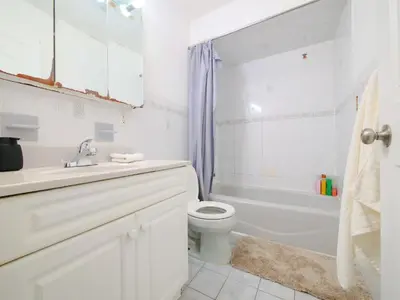 a white bathroom with a toilet and a tub and a sink at Bright Private Room with Shared Bathroom near NYC in Jersey City